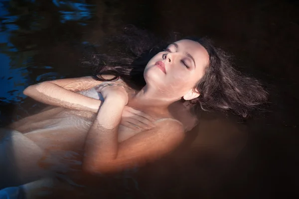 Hermosa joven acostada en el agua — Foto de Stock