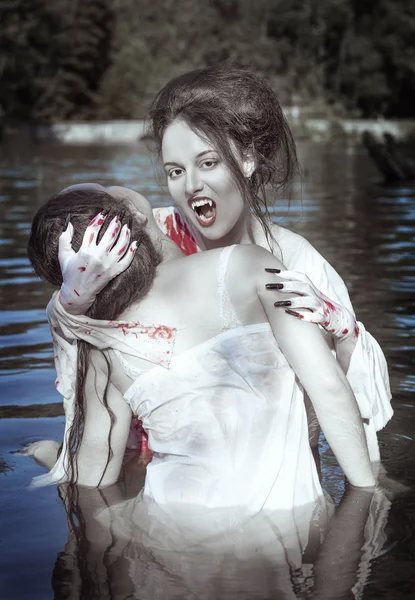 Beautiful vampire woman dressed white bloody shirt and her victi — Stock Photo, Image