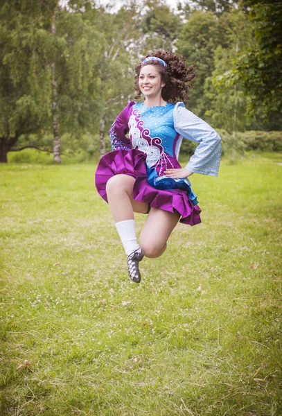 Joven hermosa chica en irlandés danza vestido saltar al aire libre —  Fotos de Stock