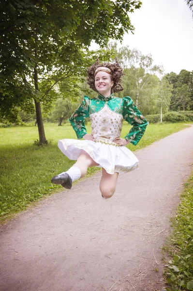 Jeune belle fille en robe de danse irlandaise sautant en plein air — Photo