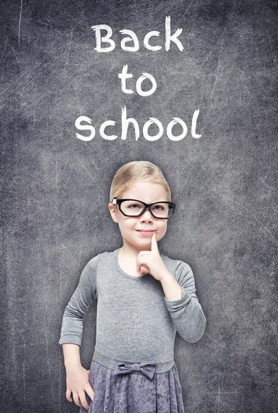 Smart beautiful little girl on the chalkboard background — Stock Photo, Image