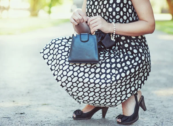 Mulher elegante com pequeno saco em suas mãos e vestido sentado — Fotografia de Stock