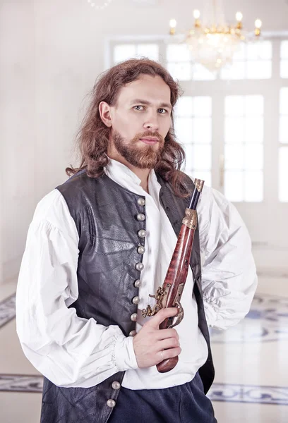 Joven hombre guapo en ropa medieval con pistola — Foto de Stock