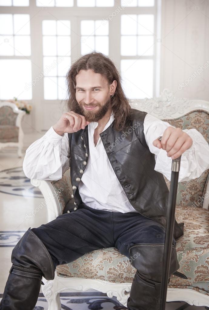 Handsome man in medieval clothes sitting in the chair
