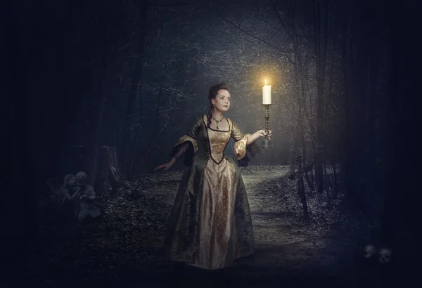 Beautiful woman with candle in medieval dress on the foggy road — Stock Photo, Image