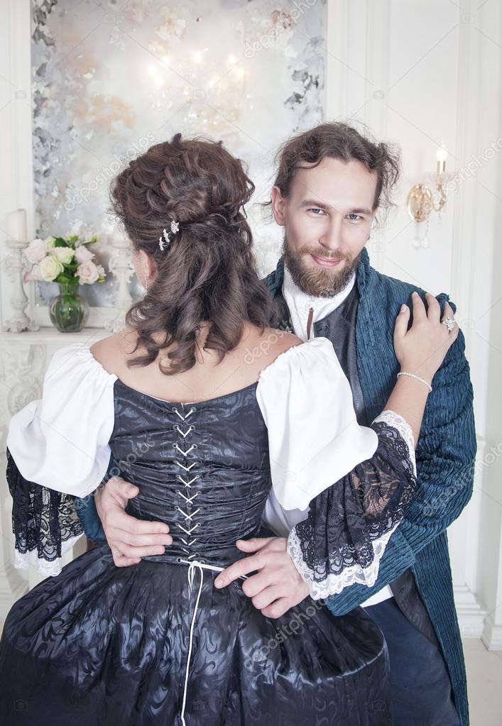 Handsome man untying corset of woman in medieval dress