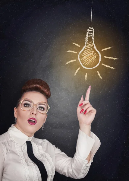 Ideenkonzept. Frau zeigt auf Lampe — Stockfoto