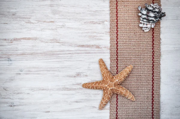 Seashells and sackcloth on the old white wood — Stock Photo, Image