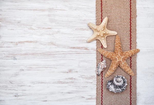 Seashells and sackcloth on the old white wood — Stock Photo, Image