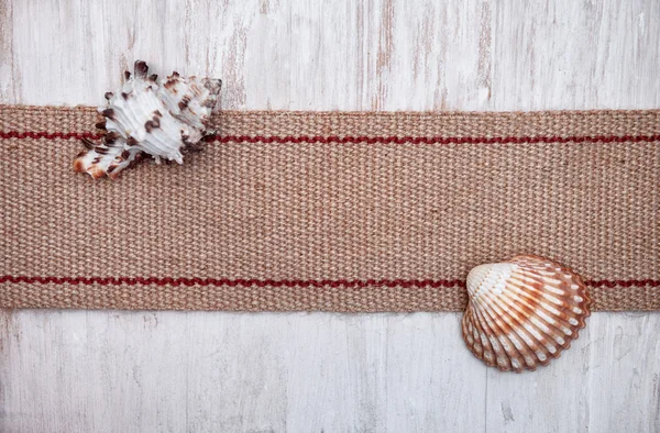 Seashells e pano de saco na velha madeira branca — Fotografia de Stock