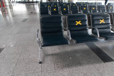 Havaalanından sosyal uzaklık. Üzerinde tabela olan havaalanı koltukları yasaktır. Uluslararası bir havaalanı salonunda COVID-19 salgını sırasında boş koltuklar