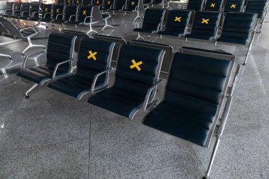 Havaalanındaki uluslararası salon boş. Havaalanındaki koltuklarda sarı yasaklama işaretleri