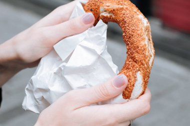 Geleneksel Türk simit 'i bir kadının elinde. Susamlı çıtır simit.