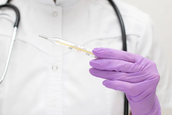 Dokter tangan dalam sarung tangan medis memegang termometer merkuri. Perawat berseragam dengan stetoskop mengukur suhu — Stok Foto