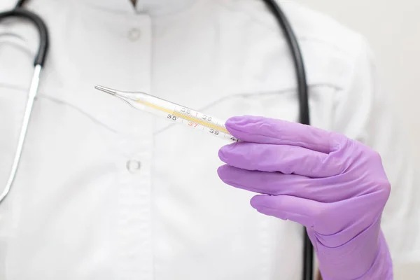 Os médicos entregam luvas médicas com termómetro de mercúrio. Enfermeira em uniforme com um estetoscópio mede a temperatura — Fotografia de Stock