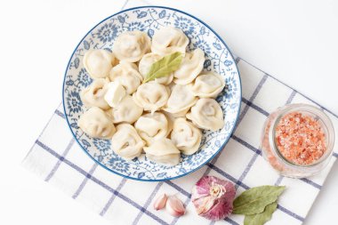 Pembe tuzlu hamur tatlısı ve mavi bir tabakta kareli havluyla sarımsak. Etli Ravioli. Geleneksel Mutfak.