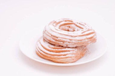 Süzme peynirli çörekler beyaz tabağa şeker serpiştirilmiş.