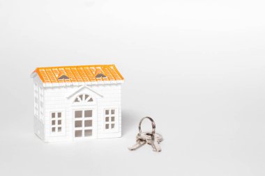 İzole edilmiş beyaz arka planda küçük ev ve anahtarlar.