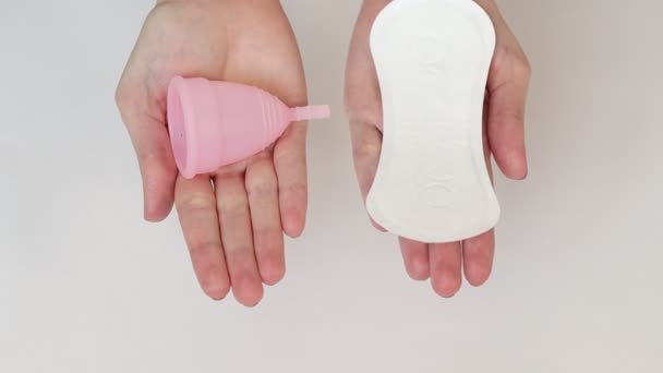 Mãos femininas segurando copos menstruais e almofada sanitária — Vídeo de Stock