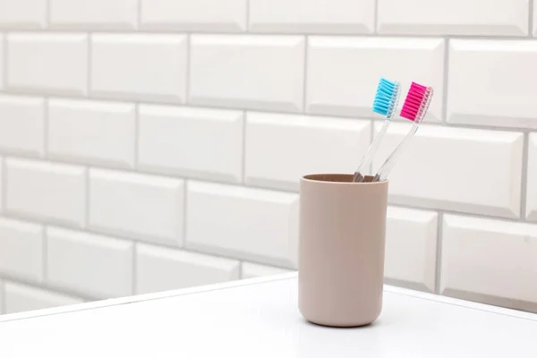 Sikat gigi dalam cangkir di kamar mandi putih — Stok Foto