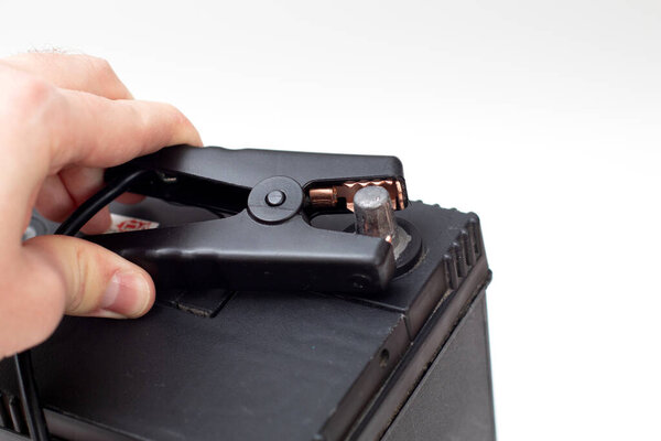 Руки держат аккумуляторы зарядки зажимы. Черно-отрицательный терминал аккумулятора