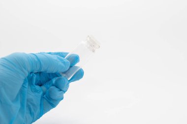 Doktor elinde grip virüsü aşısı olan mavi eldivenleri getirdi. Doktor elinde aşıyla bir şişe tutuyor. İlaç ve uyuşturucu kavramı.