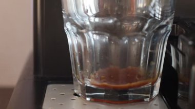 Kahve makinesi bardağa espresso kahvesi dolduruyor. Sabahları taze sade kahve içiyorum. Kahve makinesi cam şeffaf kahve fincanında espresso yapıyor..