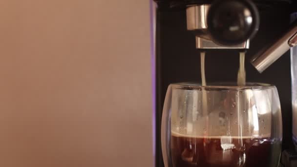 Espresso caliente que se ejecuta en la taza de vidrio doble. Cafetera vertiendo café expreso en un vaso. — Vídeo de stock