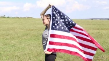 Buğday tarlasında Amerikan bayrağı sallayan mutlu bir kadın. Amerikan Bağımsızlık Günü 'nü kutluyoruz. 4 Temmuz 'da. Ulusal Amerikan bayramı.