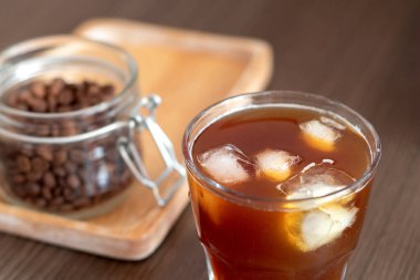 Buz küplü buzlu kahve ve tahta tabakta kahve çekirdekli kavanoz. Soğuk bira.