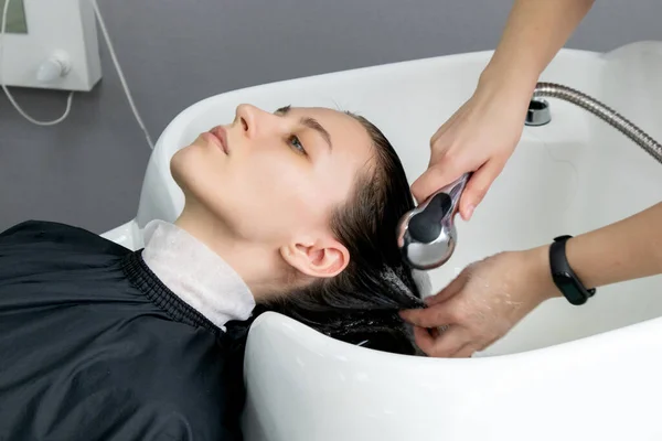 Washing hair in a hairdresser. Woman in a beauty salon. Barber washes the woman\'s head in the barbershop