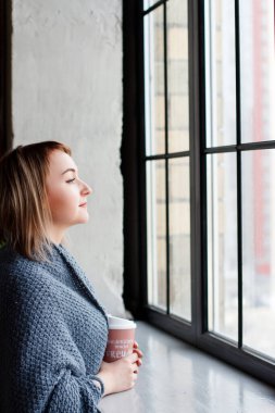Kahveli sarışın kadın. Pencere kenarında, ekose kumaşlı..