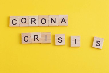 Corona Krizi ahşap harflerden yapılmıştır. Sarı arkaplanda Coronavirus kavramı.