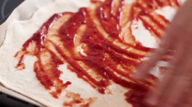 Şefin elleri Pizza Hamur 'una domates sosu sürüyor.