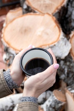 Kadın eli piknikte metal bardak tutuyor. Kahveli beyaz seyahat kupası. Dikey çekim