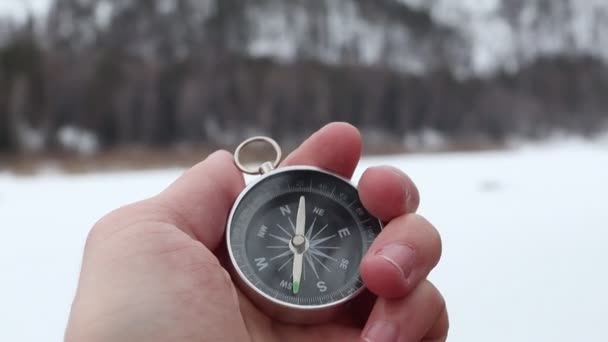Een hand met een kompas. Kompas op de besneeuwde bergen. Wandeluitrusting. Het kompas toont de richting naar de toerist — Stockvideo