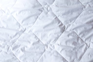 Beyaz yorganlı yatak örtüsü arka planı. Beyaz yorgan desenli yorgan tasarımı. Yumuşak sıcak battaniye.