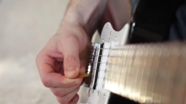 Παίζω κιθάρα με μια πένα. Τα αντρικά χέρια παίζουν έγχορδα με την κιθάρα. Παίζοντας ηλεκτρική κιθάρα — Αρχείο Βίντεο
