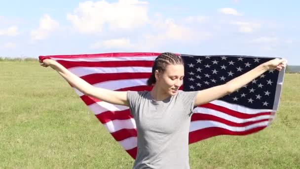 Mujer feliz sosteniendo y ondeando una bandera estadounidense en un campo de trigo. Celebrando el Día de la Independencia Americana. El 4 de julio. Fiesta nacional americana. — Vídeos de Stock