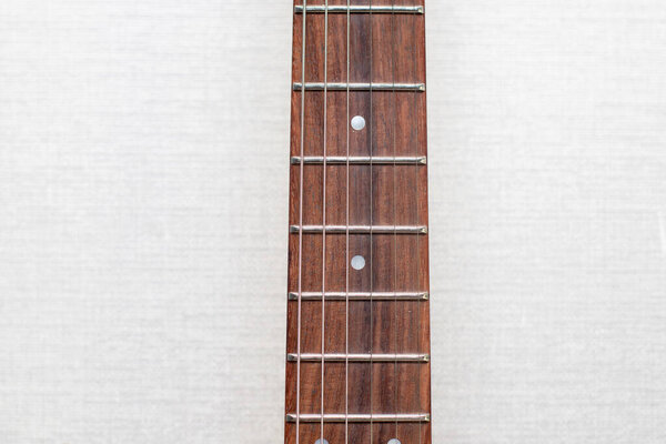 Neck of electric guitar with guitar fretboard. Part of guitar with strings.