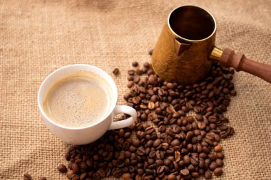 Bir fincan kahve ve kahve, yanında da kahve çekirdekleri. Kavrulmuş fasulyeli klasik Türk.