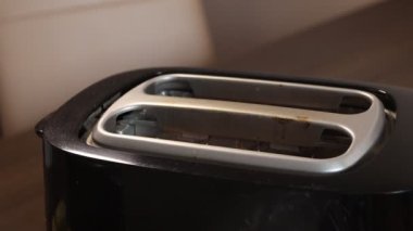 Tost makinesine ekmek dilimleri koymak. Tost makinesinden fırlıyor. Elin tost makinesinin tostunu çıkarıyor.