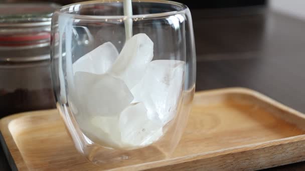 Mleko wlewa się do mrożonej kawy. Lodowa latte w podwójnej szklance — Wideo stockowe