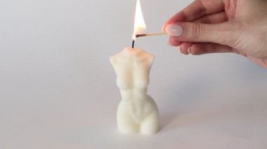 Bir kadın kibritle mum yakar. Kadın gövdesi şeklinde mum yanıyor.