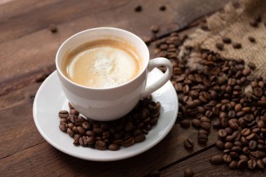 Ahşap masada taze demlenmiş kahve ve ahşap masada kavrulmuş kahve çekirdekleri..