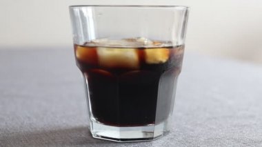 Bir bardak kahveye süt koyuyorsun. Buzlu ve sütlü soğuk kahve.