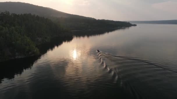 मोटर मछली पकड़ने की नाव नदी हवाई दृश्य पर तैर रही है। झील पर सूर्यास्त। नाव के बाद ड्रोन — स्टॉक वीडियो