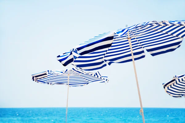 Beach umbrellas, blue sea and sky in background. — Stock Photo, Image