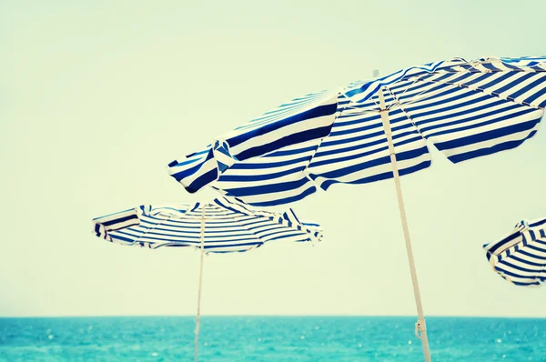 Plaj şemsiyeleri, mavi deniz ve gökyüzü arka planda. — Stok fotoğraf