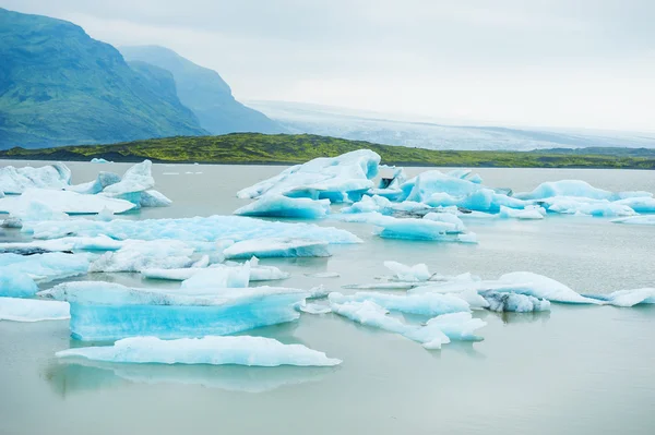 Ijsbergen in het gletsjermeer met uitzicht op de bergen. — Stockfoto